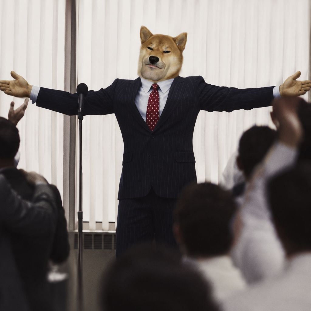 Mog Inu in a pinstripe suit, arms open, addressing a cheering crowd.